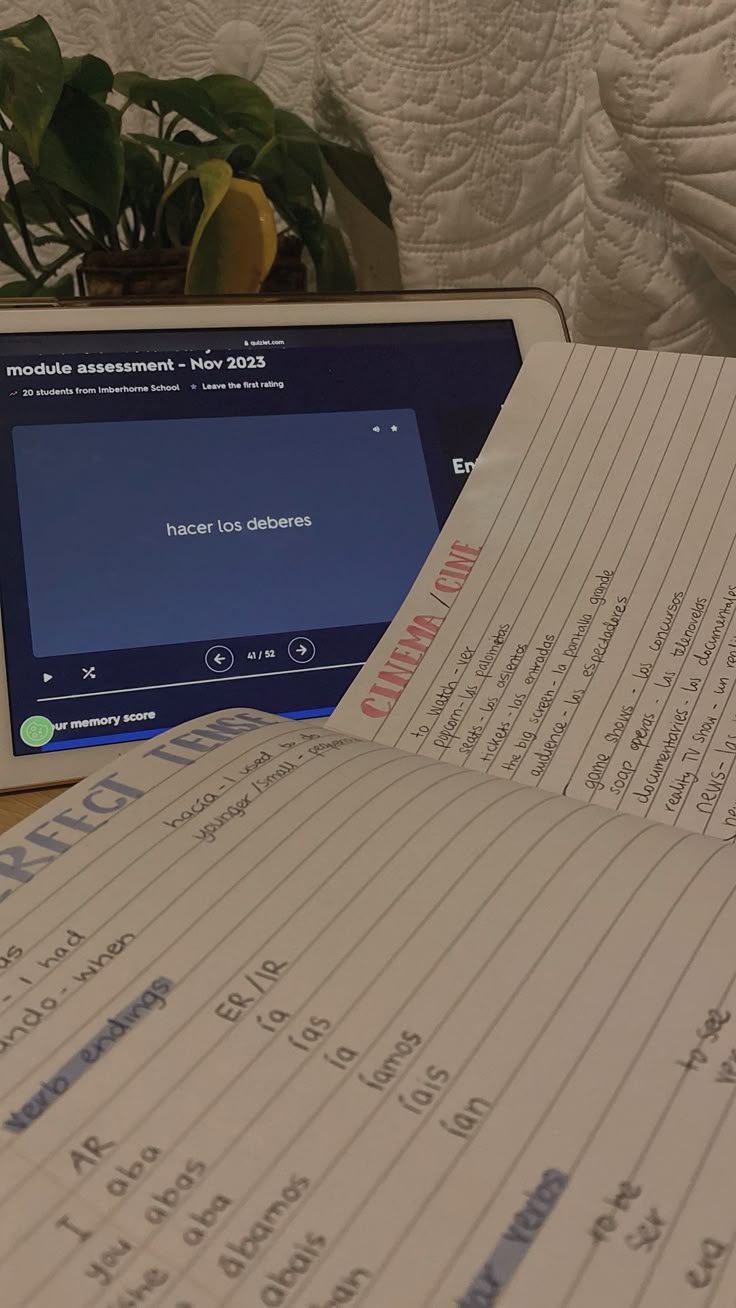 Handwritten Spanish verb notes beside a tablet flashcard.